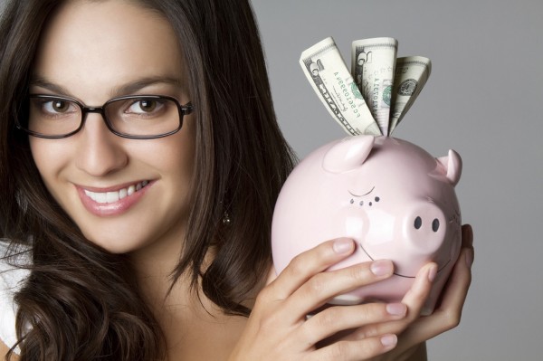 Smiling girl holding piggy bank money